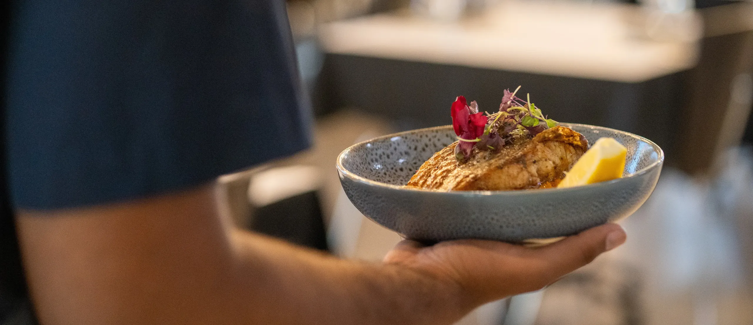 Waiter holding plate of food in hand.